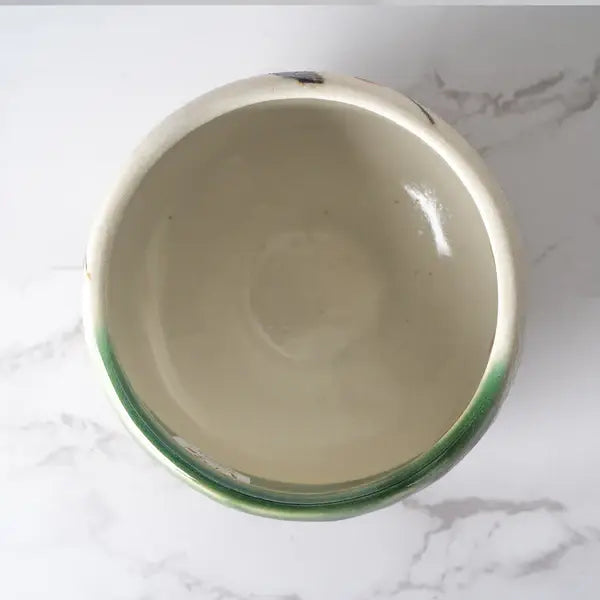 Ceramic bowl with green rim on a marble surface