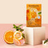 Kombucha tea packaging with oranges and a glass of tea on a pink background