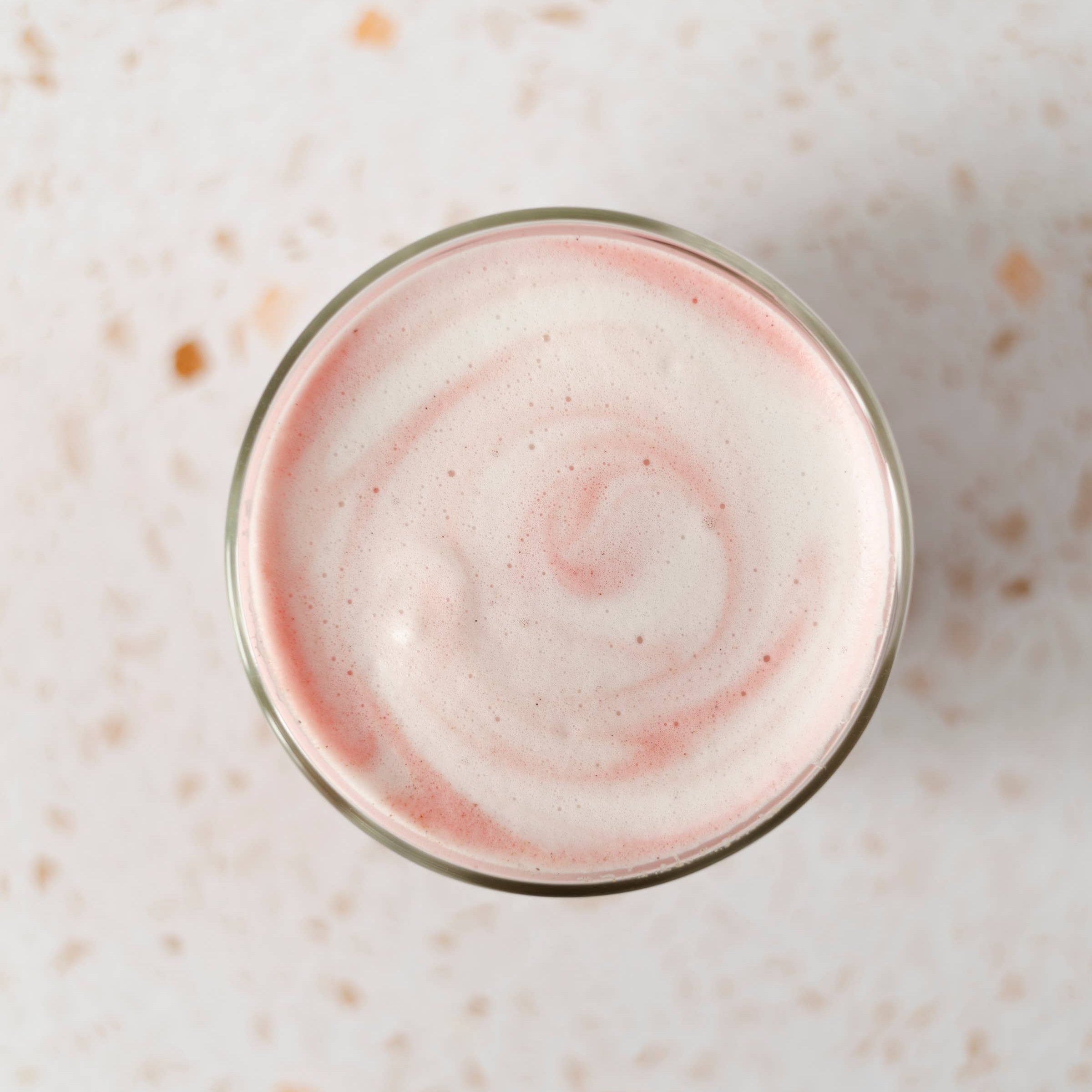 Glass with pink and white swirl on a light speckled surface