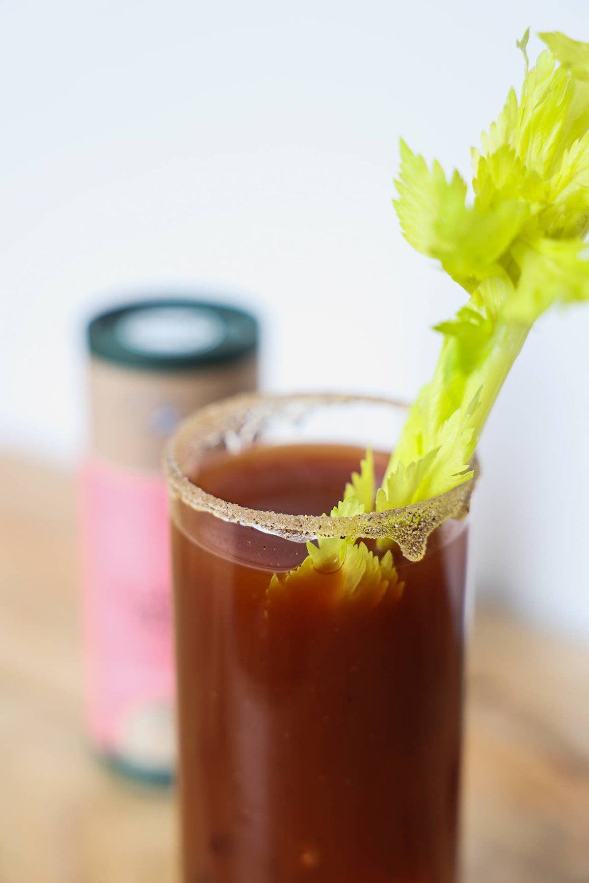 Glass of Bloody Mary with celery garnish on a wooden surface