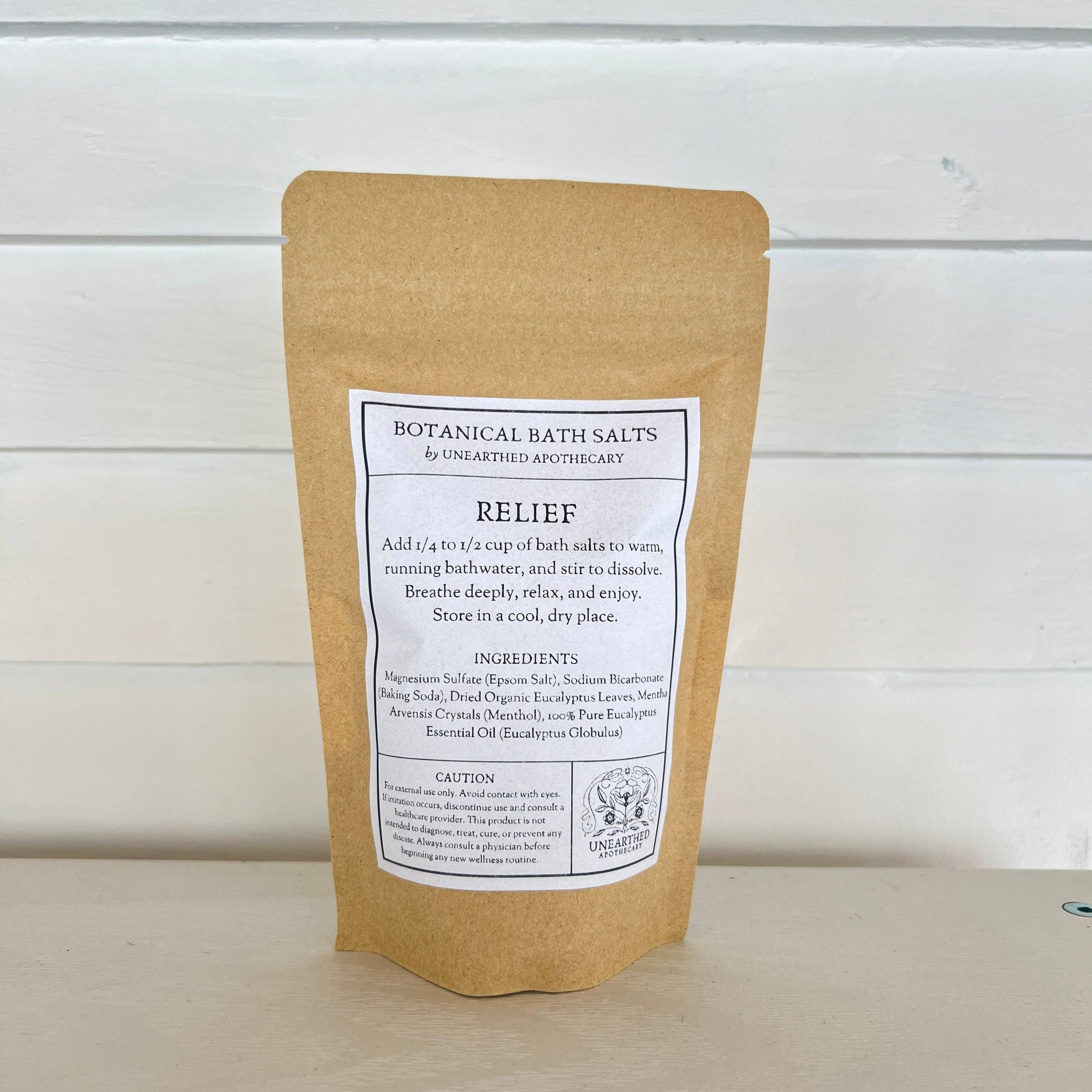 Kraft paper packaging of botanical bath salts with a label on a wooden surface.