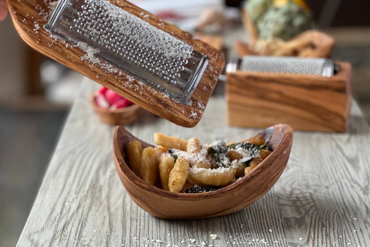 Cheese being grated over a Italian Olivewood Serving Bowl with gnocchi