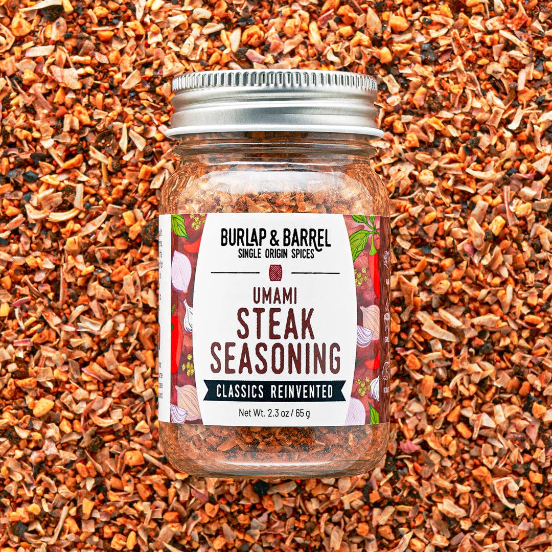 Jar of Burlap & Barrel Umami Steak Seasoning on a background of spice mix