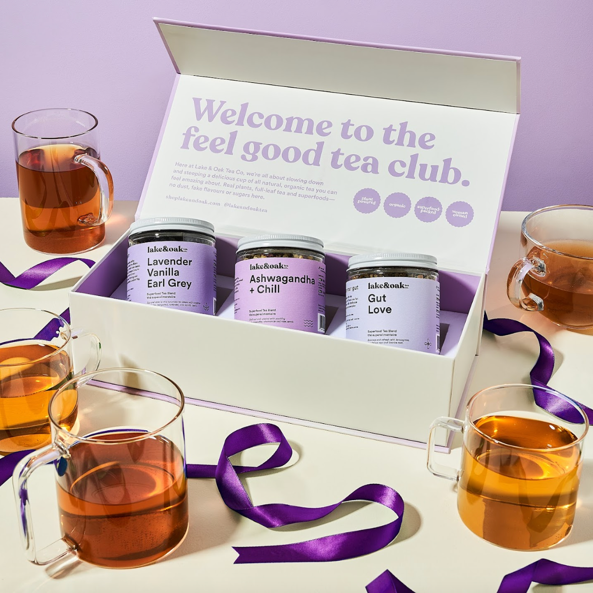 Tea club subscription box with tea jars and cups on a light purple background