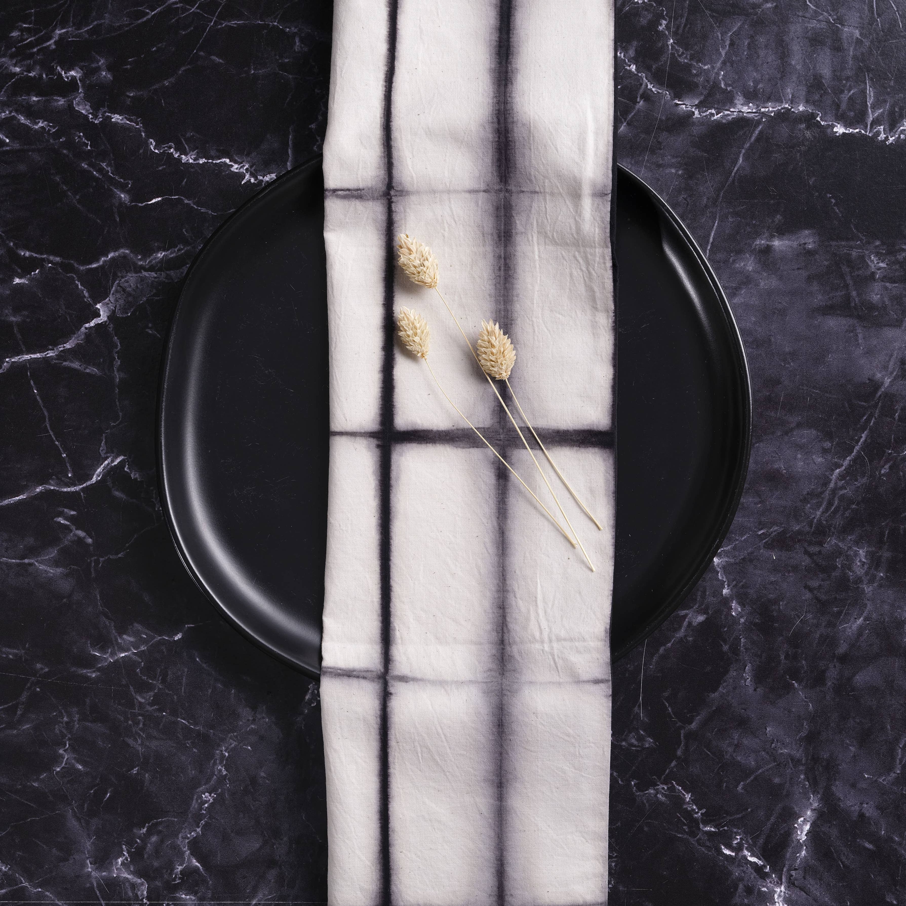 Black plate with a white napkin featuring window design on a dark marble surface