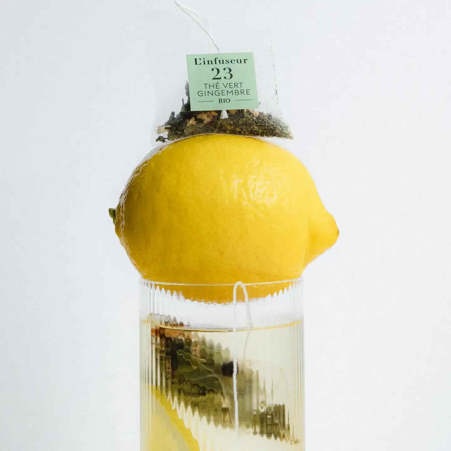 Tea bag with lemon and ginger in a clear container on a white background