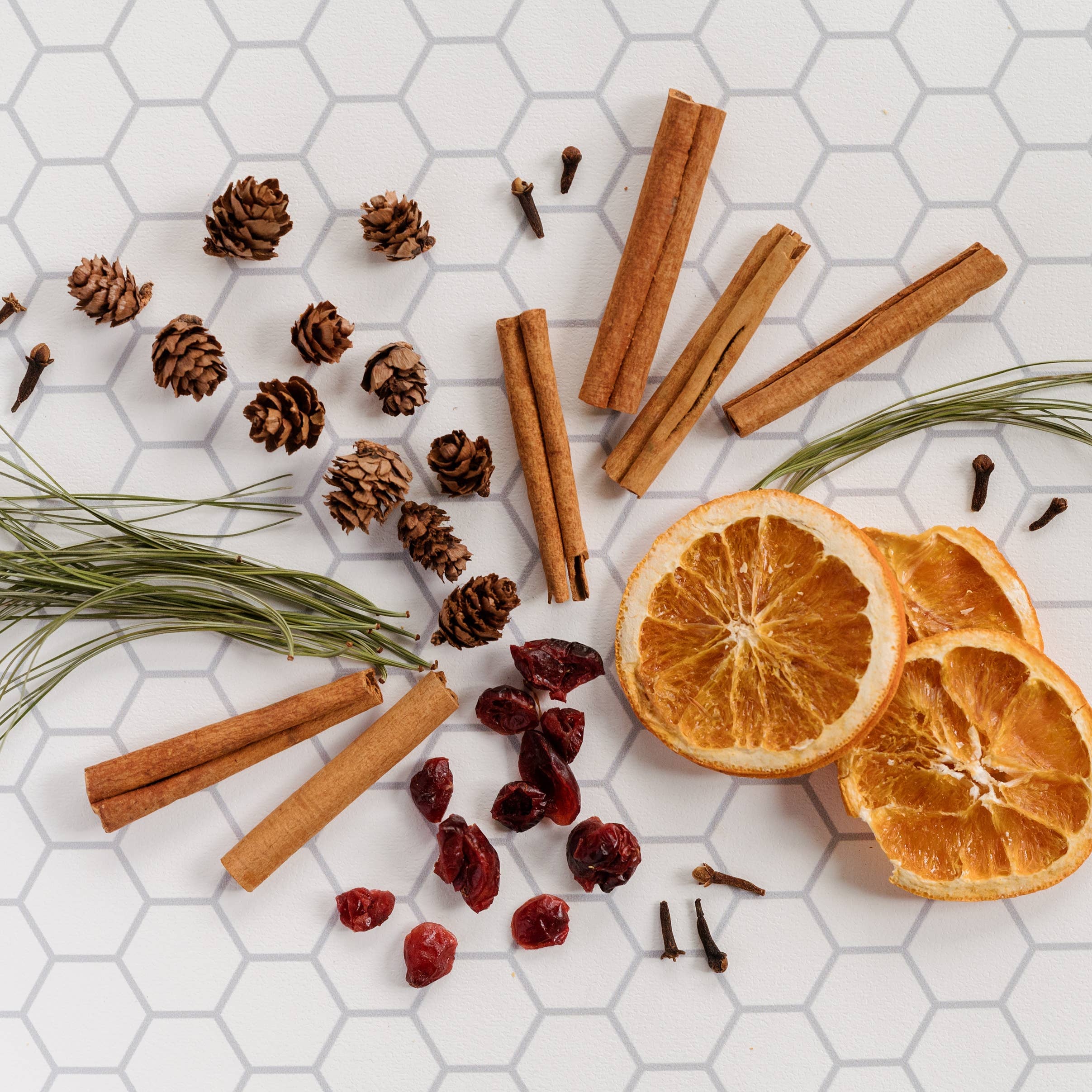 Spices and dried oranges on a hexagonal white tile background