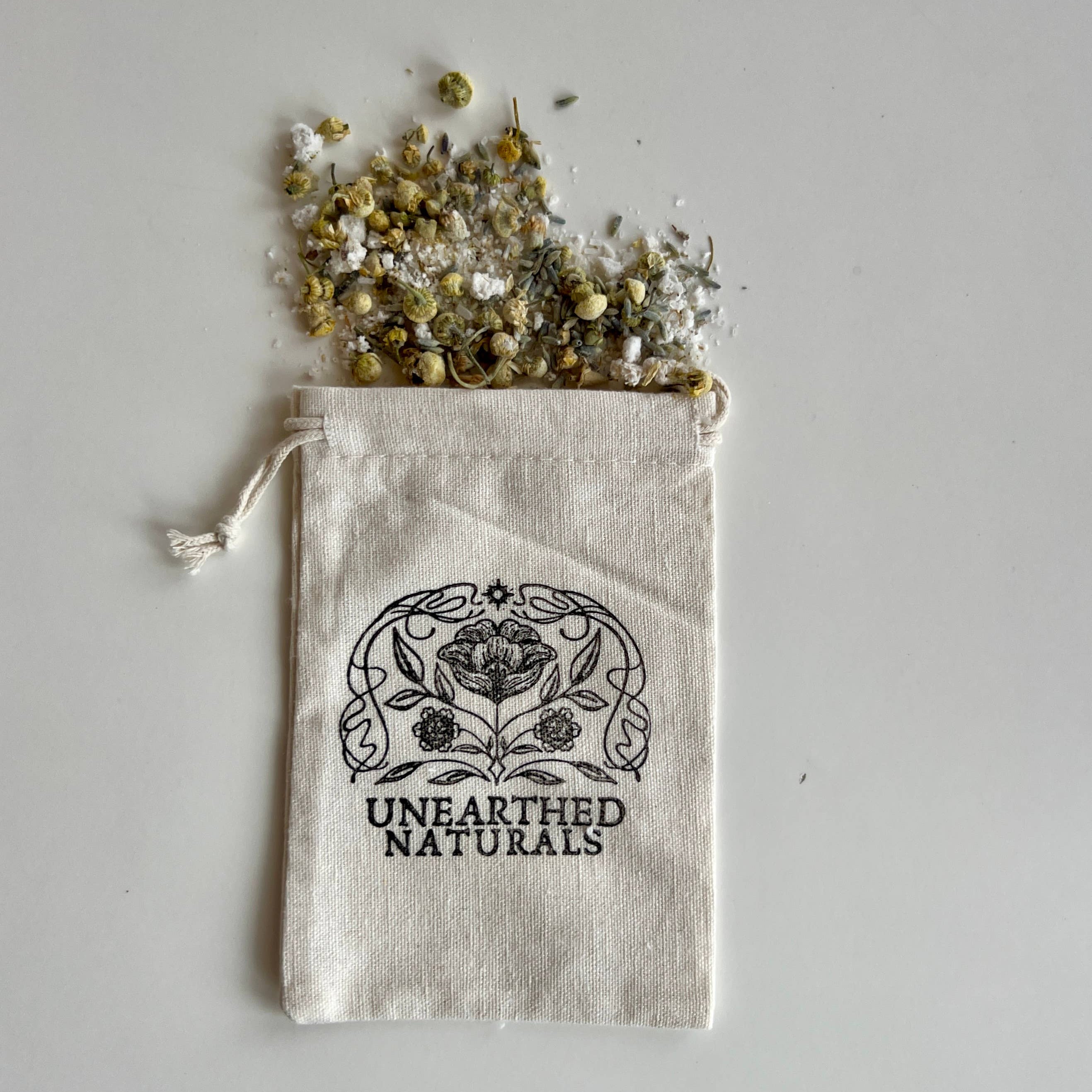 Mud pack with herbs spilling out of a bag labeled &