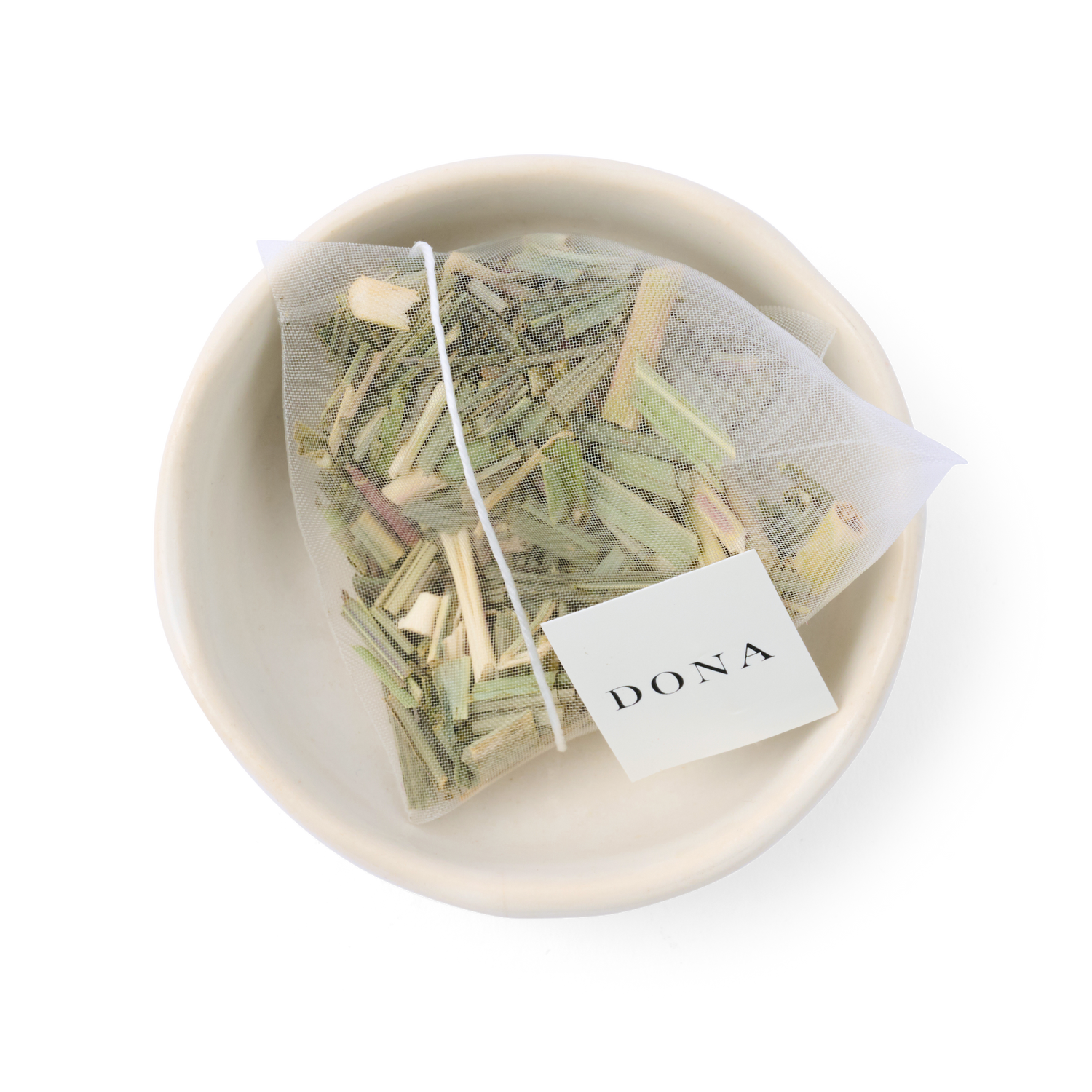 Tea bag with herbs in a white bowl on a white background, featuring the brand &