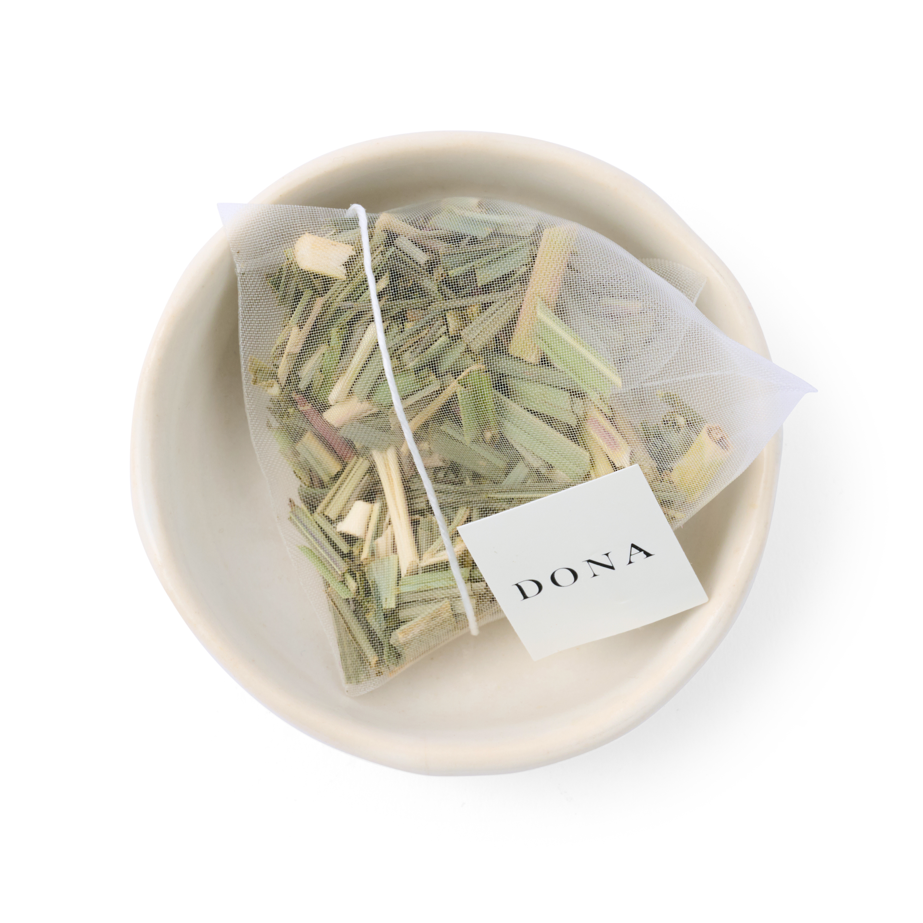 Tea bag with herbs in a white bowl on a white background, featuring the brand &