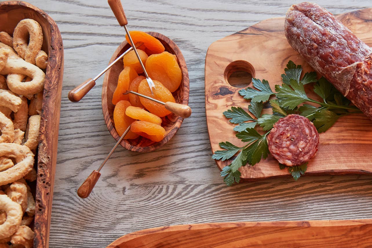 Italian Olivewood Aperitivo Bowl with dried apricots next to a wood platter with salami