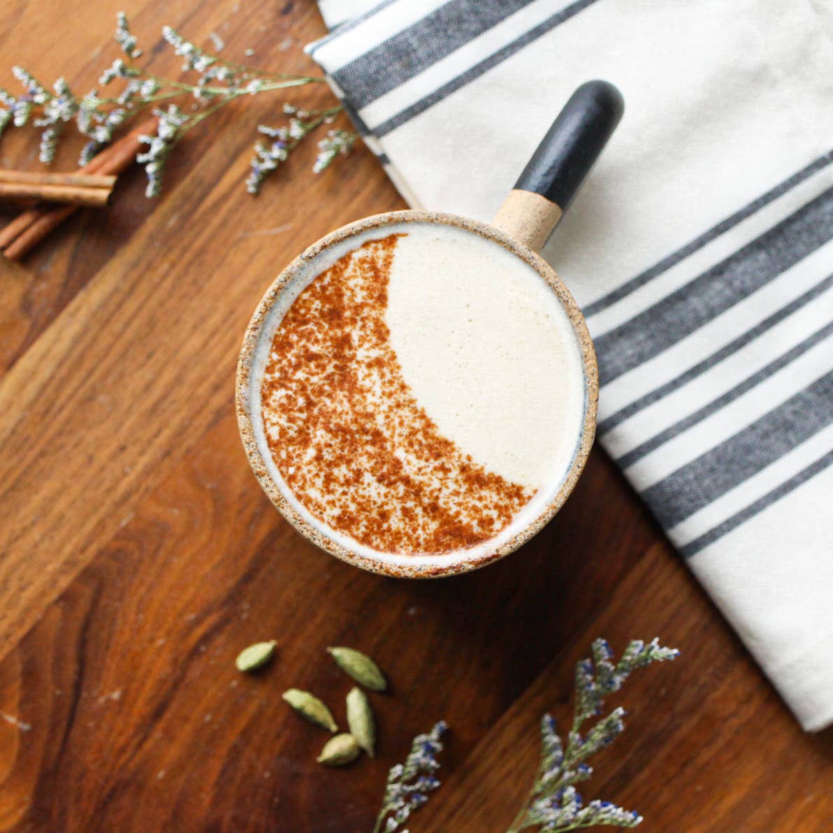 Tea in a small pot on a wooden surface with cinnamon sticks and lavender.