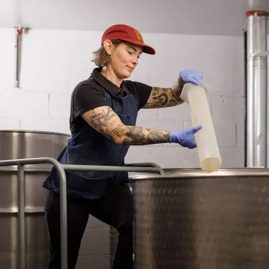 Person in a brewery holding a large container of liquid
