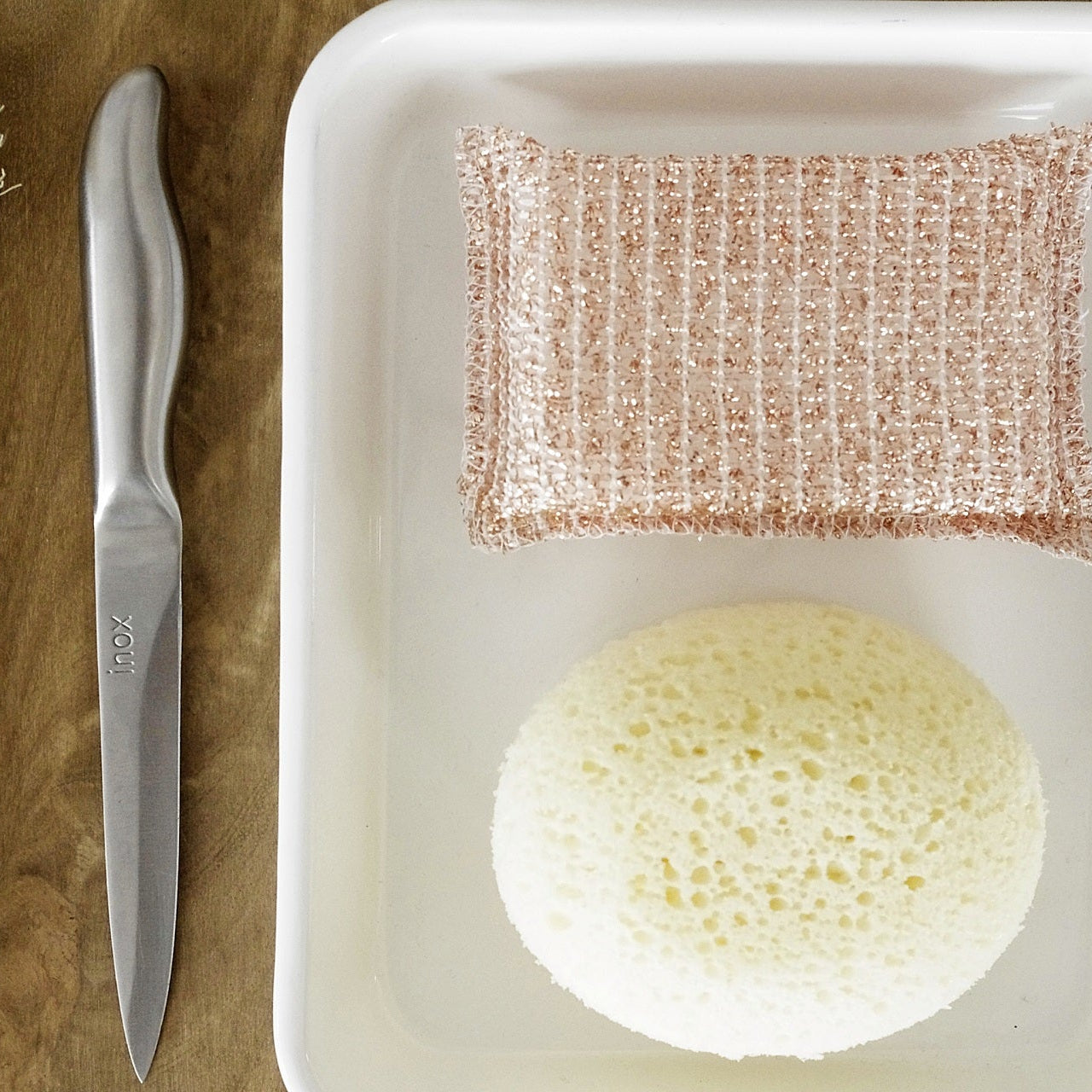 Cleaning tools including a brush, knife, and sponges on a wooden surface.
