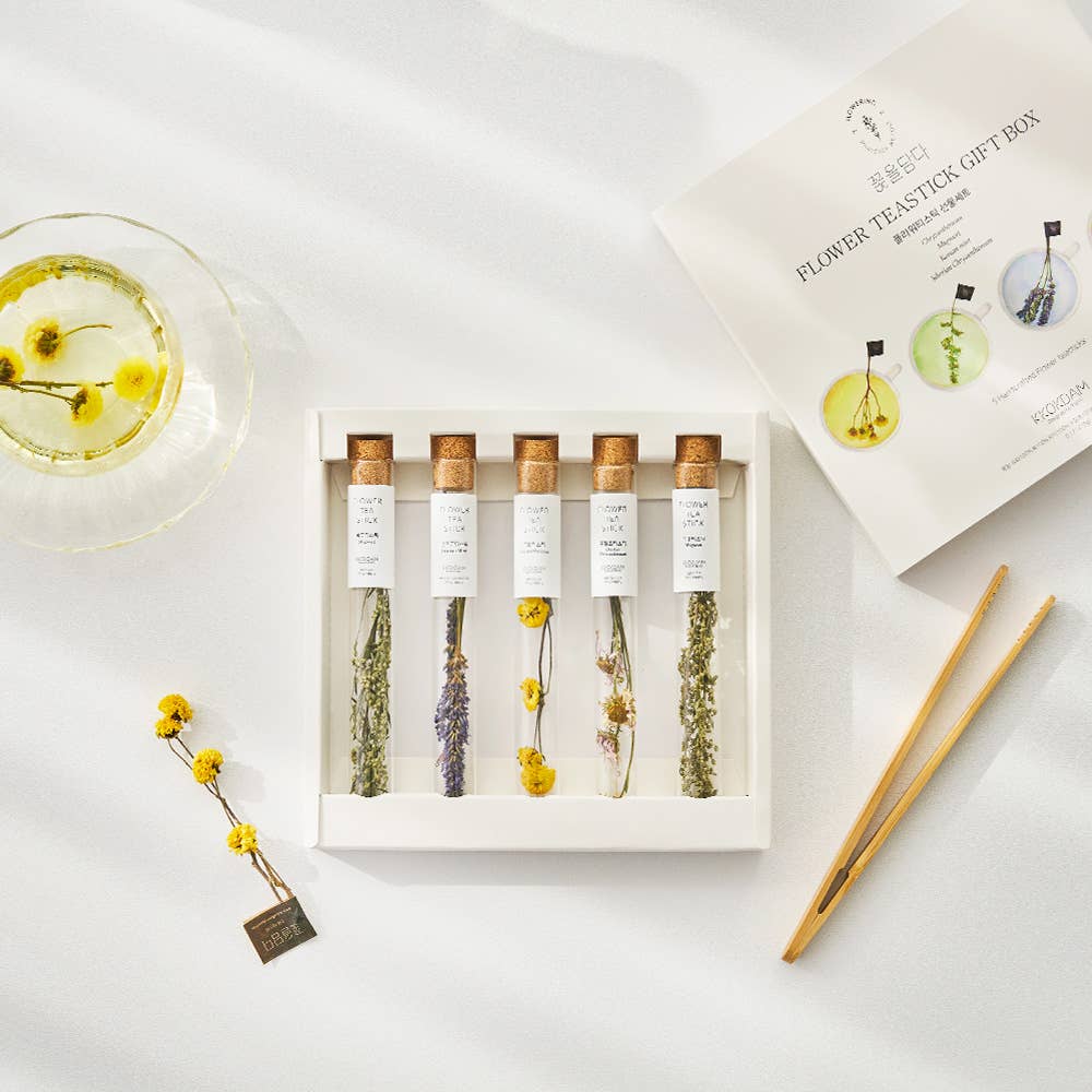 Set of flower tea sticks in a white box with packaging on a light surface.