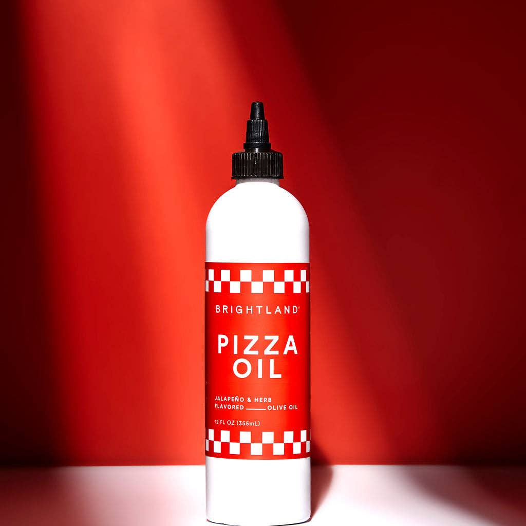 Bottle of Brightland Pizza Oil against a red background