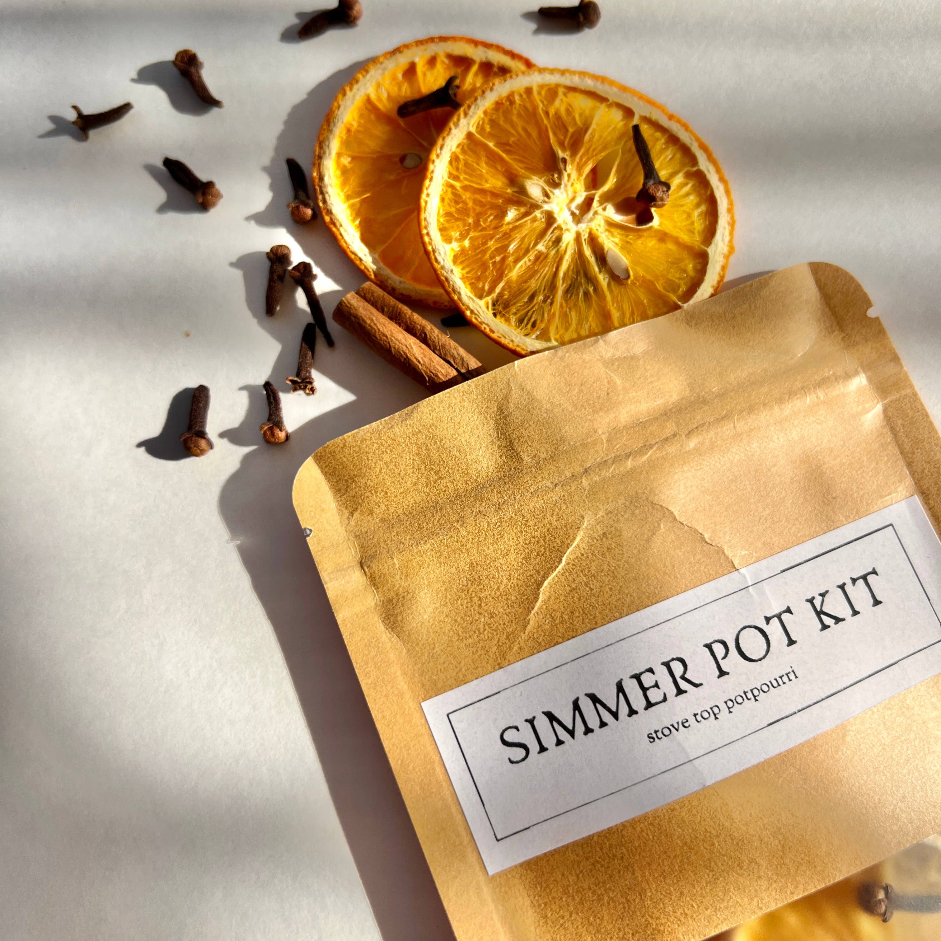 Simmer pot kit with dried oranges, cinnamon sticks, and cloves on a light background