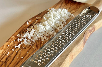 Close up of a coarse Italian Mandolin Paddle Grater and grated cheese