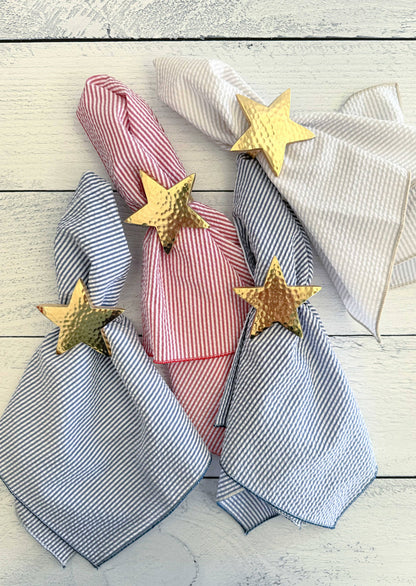 Striped napkins with gold star napkin rings on a wooden surface