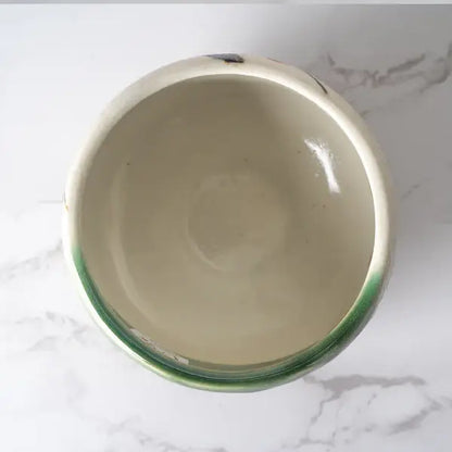 Ceramic bowl with green rim on a marble surface