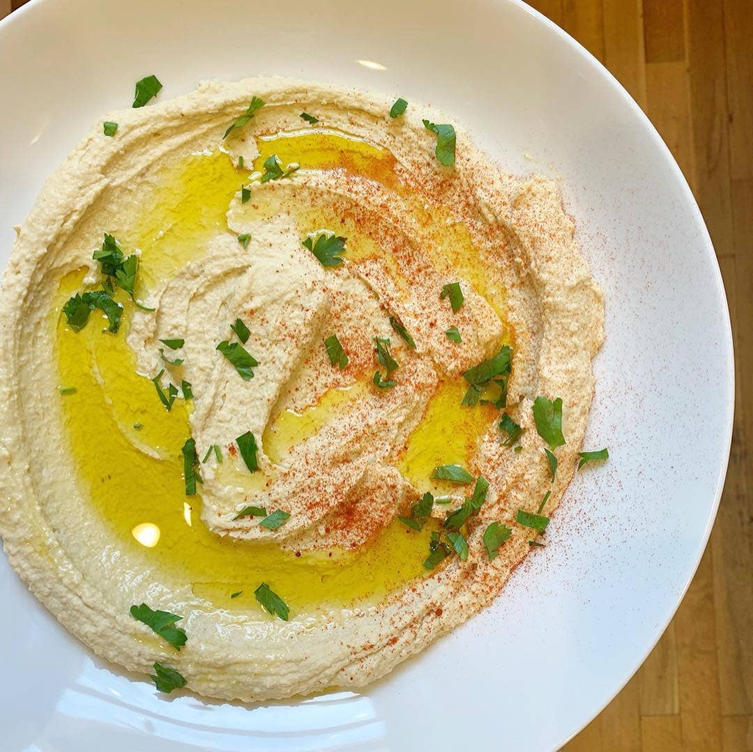 Hummus with olive oil, paprika, and herbs on a white plate
