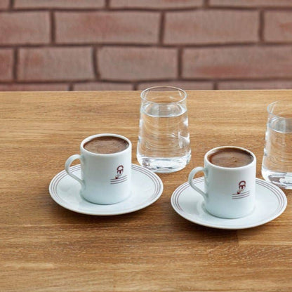 Two espresso cups with saucers on a wooden table with a brick wall background