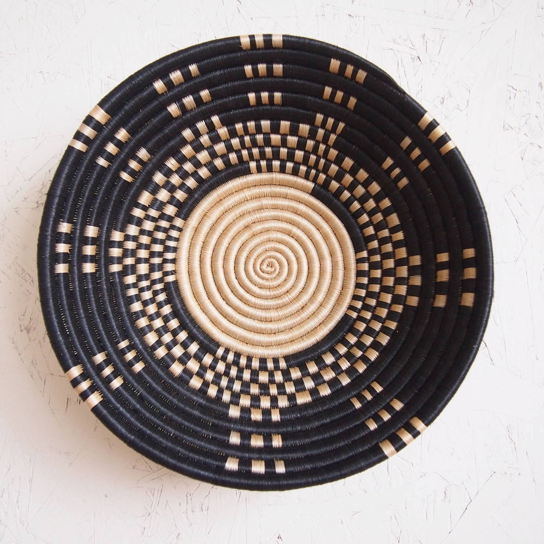 Woven basket with black and beige pattern on a white background