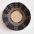 Woven basket with black and beige pattern on a white background