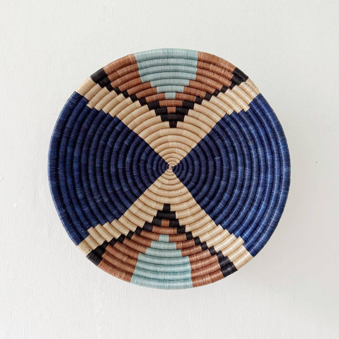 Round woven basket with geometric pattern on a white background
