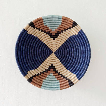 Round woven basket with geometric pattern on a white background