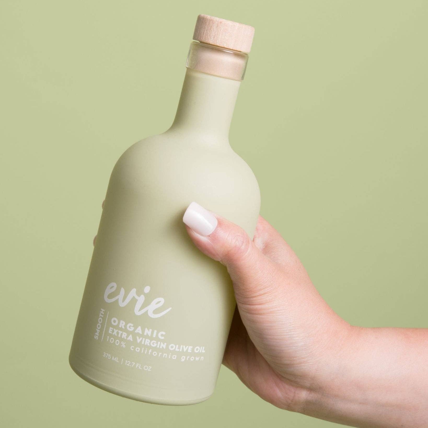 Hand holding a light green bottle labeled &