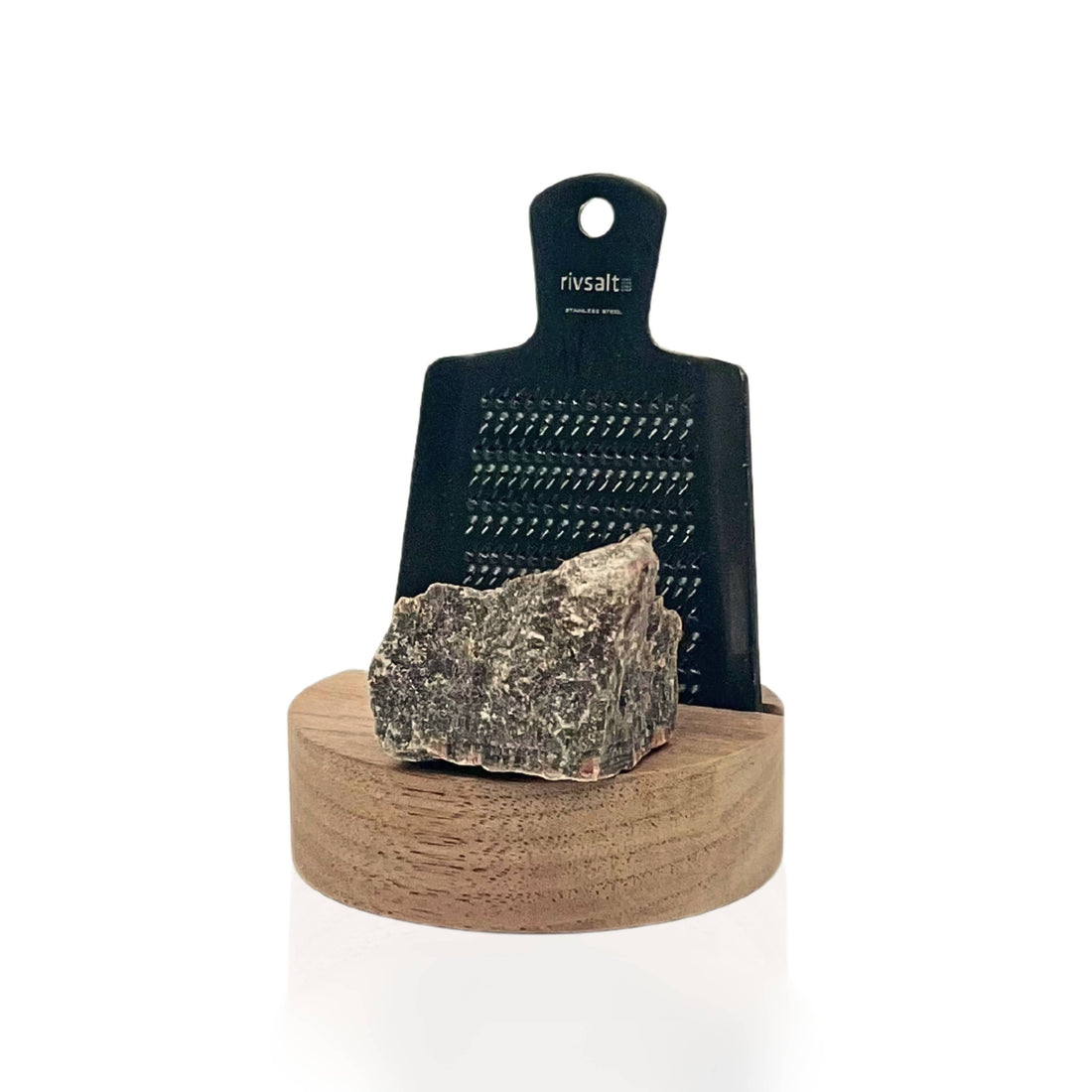 Black grater with a rock on a wooden base on a white background