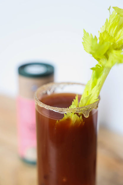 Glass of Bloody Mary with celery garnish on a wooden surface