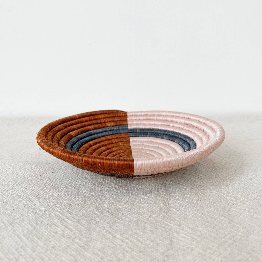 Woven basket with two-tone design on a light fabric background
