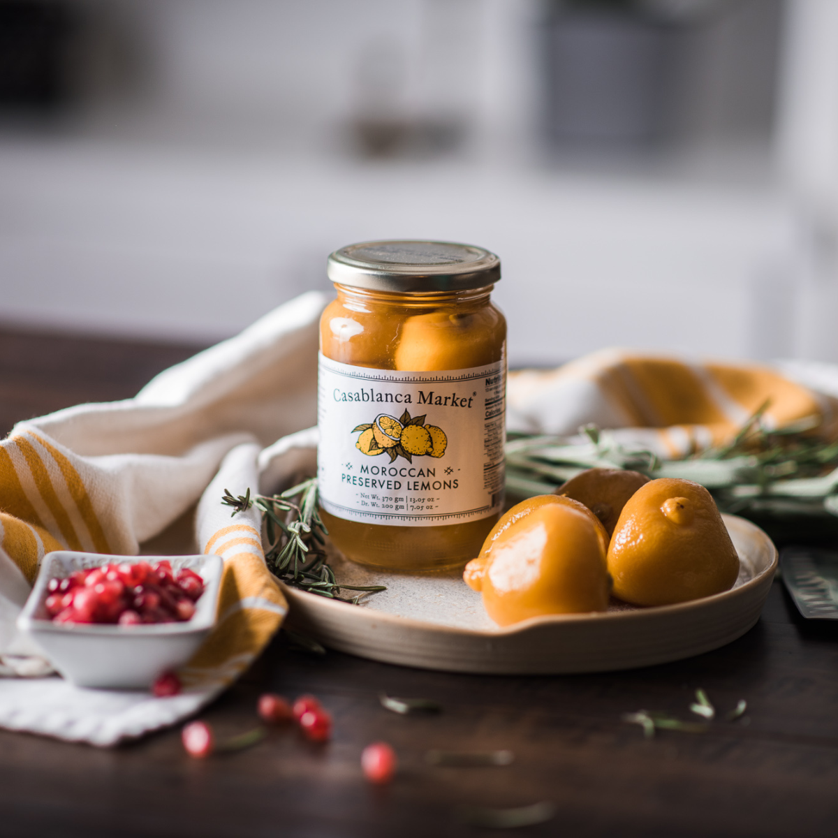 Jar of preserved lemons on a table with lemons and herbs
