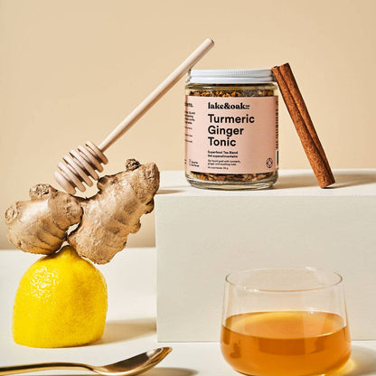 Jar of Turmeric Ginger Tonic with ingredients on a beige background