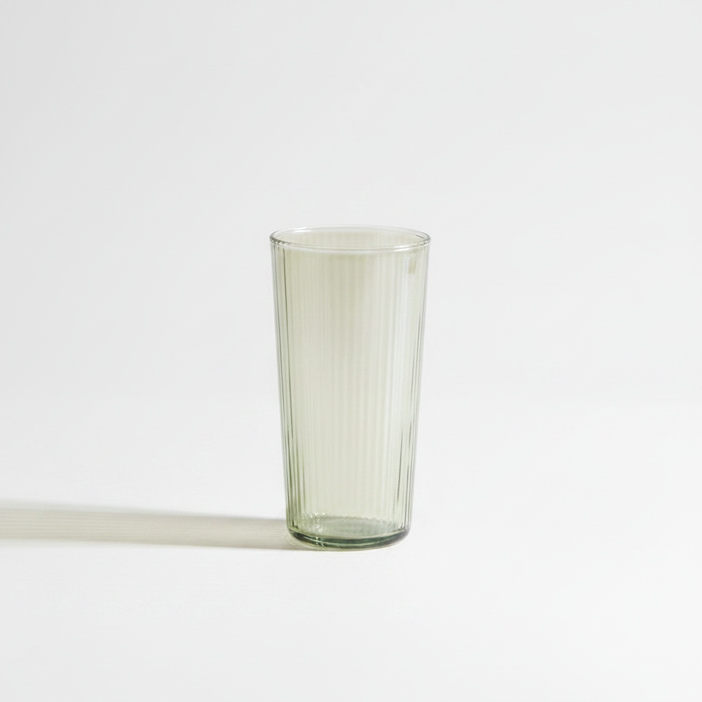 A tall glass tumbler, standing on a clean white background with a soft shadow to the left.
