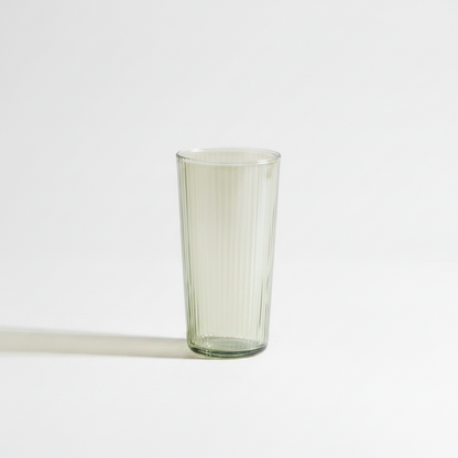 A tall glass tumbler, standing on a clean white background with a soft shadow to the left.