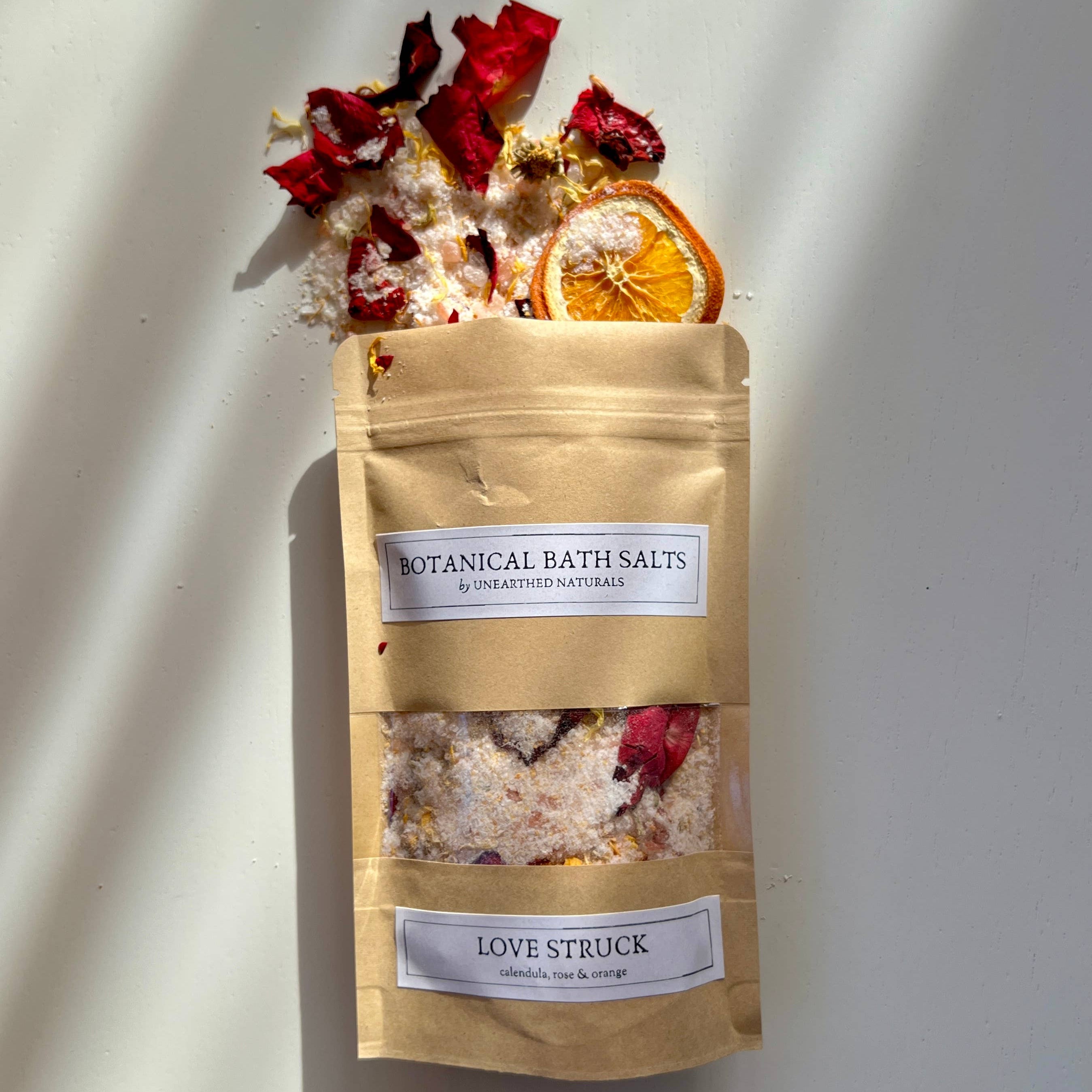 Bag of botanical bath salts with dried flowers and fruits on a white background
