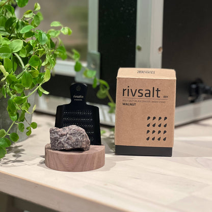 Rivsalt salt grinder and packaging on a wooden surface with a plant in the background