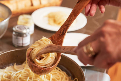 Person twirling pasta in an Italian Olivewood Soup and Pasta Ladle