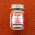 Jar of Burlap & Barrel Low & Slow Chili Powder on a textured red background