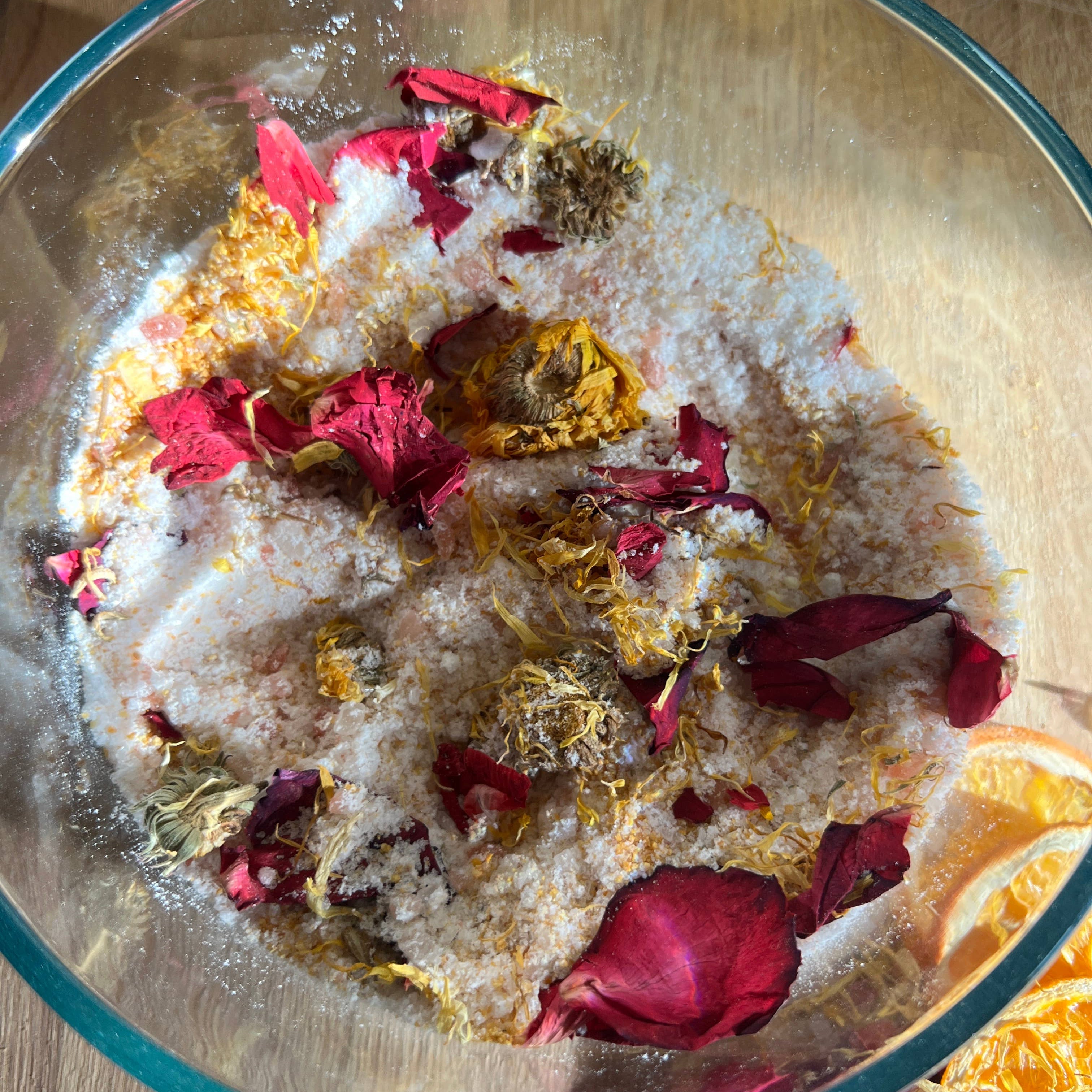Glass bowl with salt and dried flowers on a wooden surface