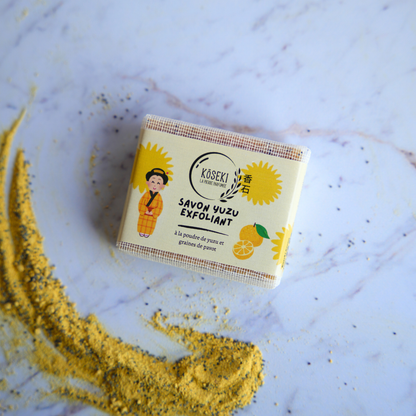 Käseki Yuzu Exfoliating Soap bar on a textured surface with yellow powder.