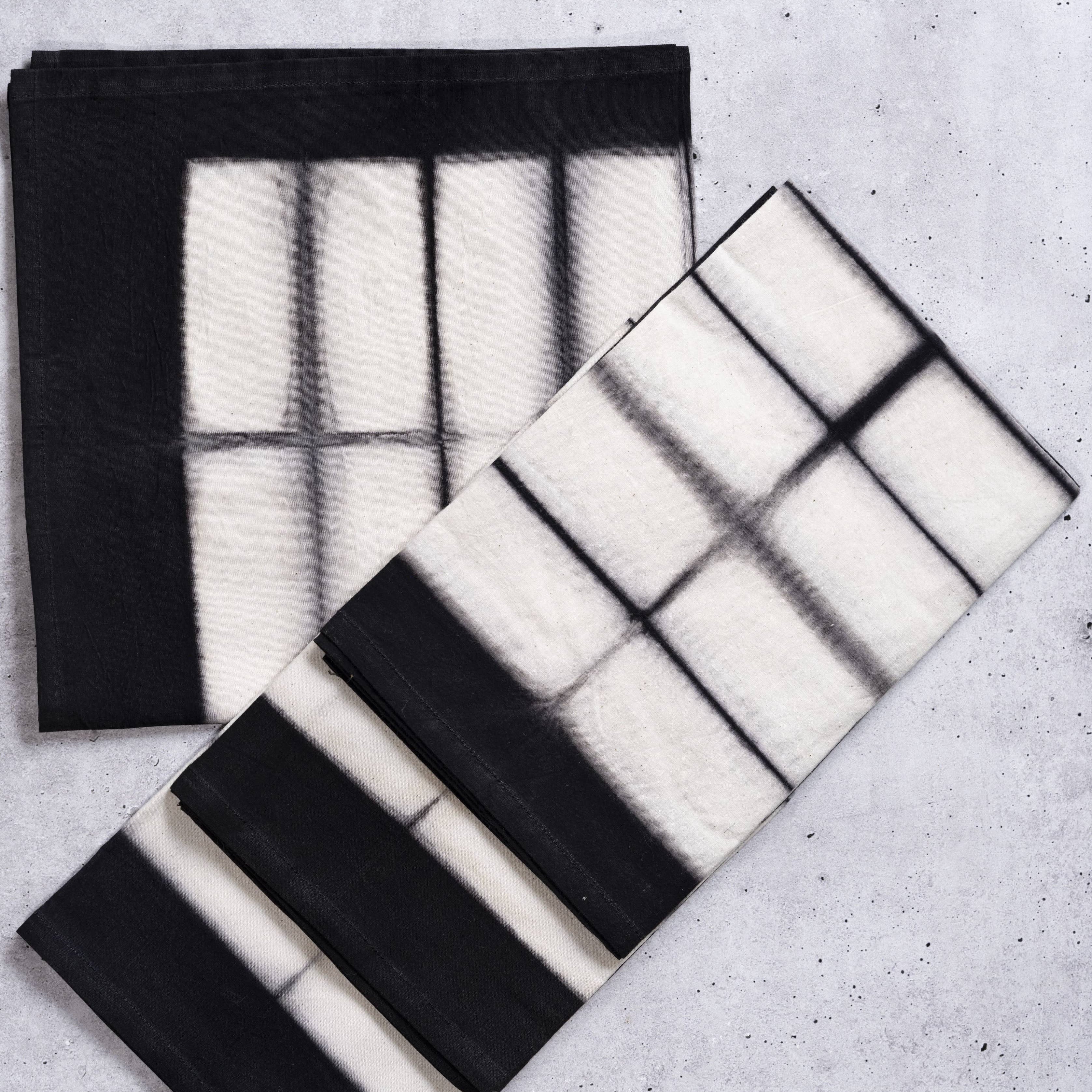 Two black and white patterned cloths on a textured surface