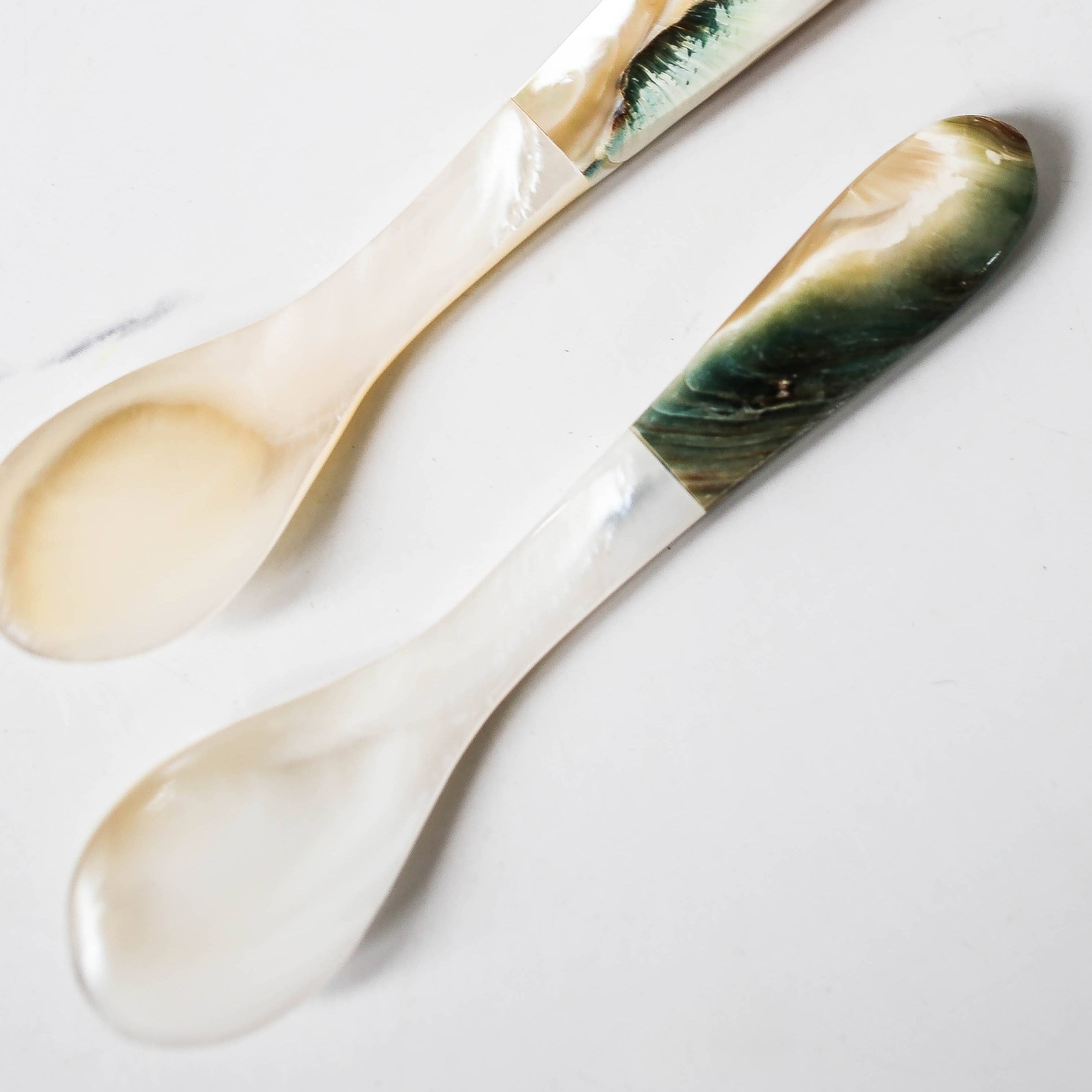 Two marble-patterned spoons on a light gray background