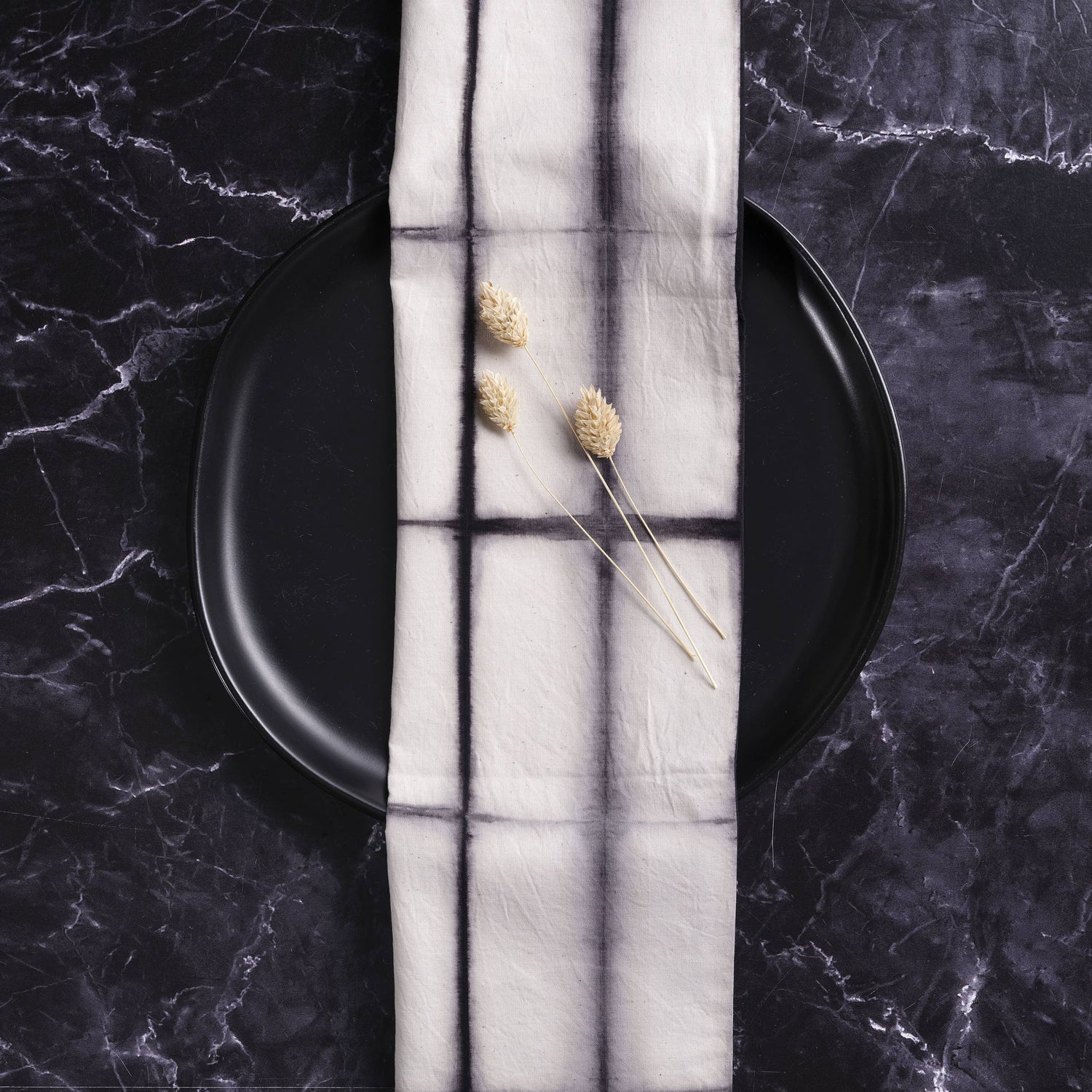 Black plate with a white napkin featuring window design on a dark marble surface