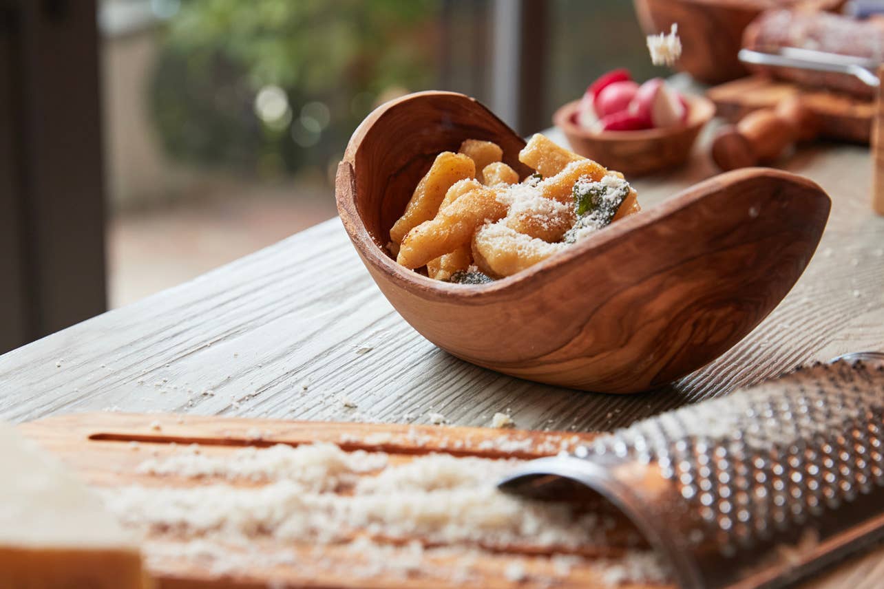 Italian Olivewood Serving Bowl with gnocchi and a cheese grater in the foreground