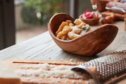 Italian Olivewood Serving Bowl with gnocchi and a cheese grater in the foreground