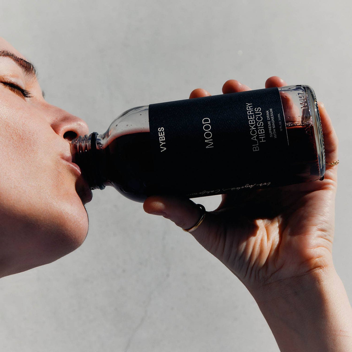 Person holding a bottle of VYRES Blackberry Gin against a plain background